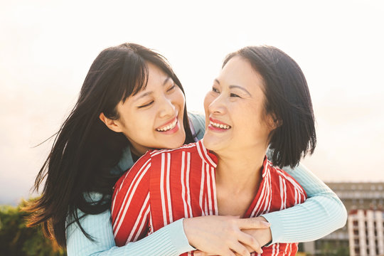 Happy Asian mother and daughter having fun outdoor - Chinese family people spending time together outside - Love, relationship and parenthood lifestyle concept
