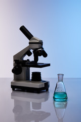glass flask with colorful blue liquid near microscope