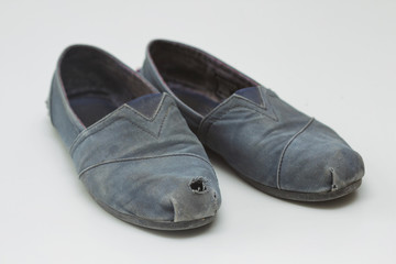 Old dirty rag boots with a hole. White background. Waste recycle. Problem of garbage. Reuse materials. Women's shoes.