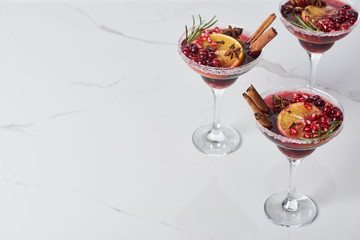 christmas cocktails with orange, pomegranate, cinnamon on marble table