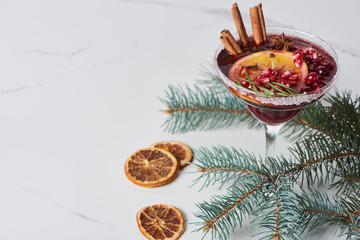 christmas cocktail with orange, pomegranate and cinnamon on marble table