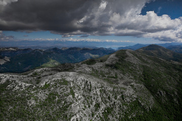 Fototapeta na wymiar landscape below (aerial photo from a paraglider) with green mountains, severe with clouds. Montenegro