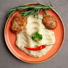 mashed potatoes and meat cutlets in an orange plate