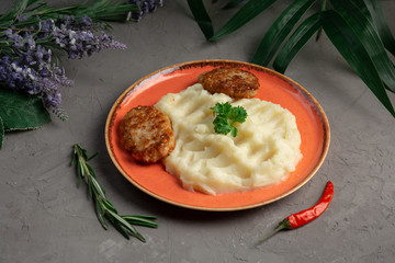 mashed potatoes and meat cutlets in an orange plate