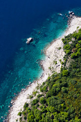 Fototapeta na wymiar Wooded shore, stones and sea from above. landscape below (aerial photo from a paraglider) with the coast and the blue sea, Montenegro