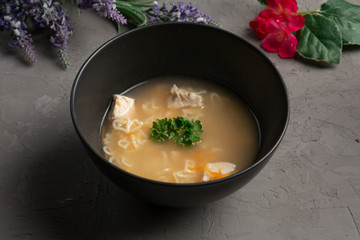 heart-shaped chicken noodle soup in a black plate