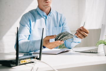 cropped view of businessman holding wire near plugged router