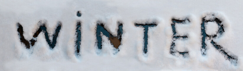 Wintertime concept. Winter word written with finger on a snow melted of car window.