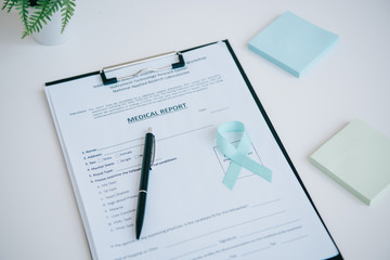 blue awareness ribbon on medical report near pen and sticky notes