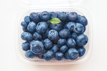 ripe blueberries in a transparent container on a white background