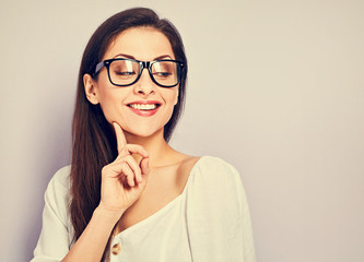 Beautiful positive young happy woman in eye glasses thinking and looking down in casual shirt on empty copy space. Closeup