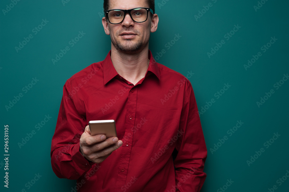 Wall mural portrait of a positive young man in glasses with phone