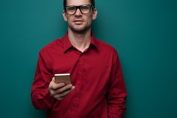 Portrait of a positive young man in glasses with phone