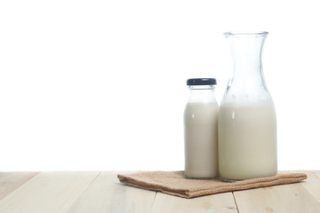 Milk in glass and in jar on table isolated on white background