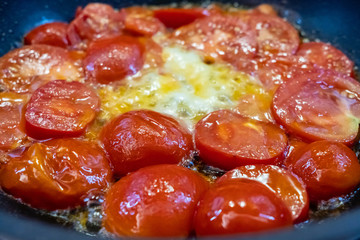 Appetizing fried red sweet tomatoes with butter and vegetable oil in a hot pan. Delicious homemade...
