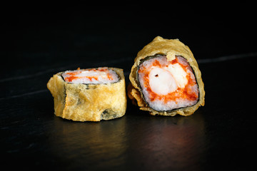 pair of rolls tempura ebi itame with krab close-up on a dark background © Said Ramazanov