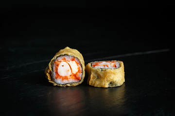 pair of rolls tempura ebi itame with krab close-up on a dark background © Said Ramazanov