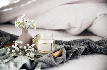 beautiful little vase, candle and flowers metal tray on the bed with white linens