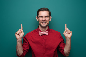 Portrait of a cute young man showing fingers on a green background