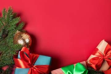 Three bright christmas gifts with colorful atlas ribbons on solid red background