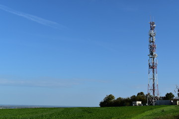 Telecommunication tower with radio antennas in a green environment. Electromagnetic and microwaves background/pollution.
