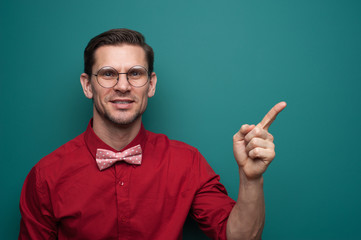 Portrait of a cute young man showing finger on a green background