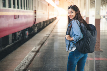 Fototapeta premium Portrait of young asian woman smiling and waiting at train station. Travel concept.