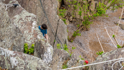 Male climbing rocks and looking down at climber below