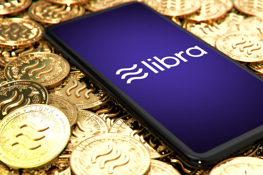 WROCLAW, POLAND - JUNE 20th, 2019: Facebook announces Libra cryptocurrency. Smartphone withLibra logo on the screen is laying down on Libra concept coins - 3D rendering