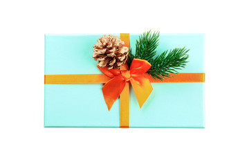 Christmas composition. Blue box tied with an orange ribbon isolated on a white background. Fir branches. Cone. Flatlay. Top view.