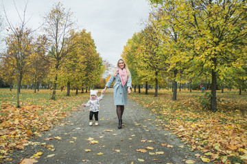 Fototapeta premium Young mother and her little daughter at beautiful autumn park