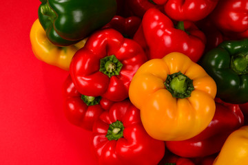 Fresh red, yelow, green bell pepper on a red background.