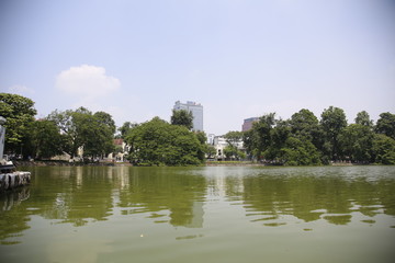 Fototapeta na wymiar The city hides behind the trees of Lake Hanoi, Vietnam