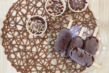 Top view of raw vegan ice cream from bananas and coconut cream topped with natural chocolate lay on round wicker tablecloth. Delicious natural organic homemade dessert. Healthy sweets concept