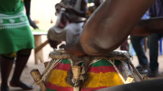 Slow motion close up of man playing a traditional Togolese drum and woman dancing in Africa