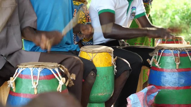 Medium shot of men playing the Togolese drums while I woman dances into frame