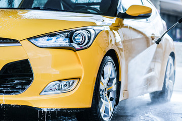 Man cleaning vehicle with high pressure water jet. Car wash details or close up.