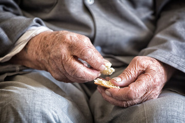 Hands of an old man with a slice of bread