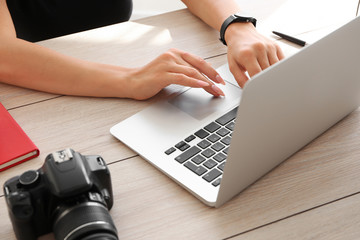 Young female photographer working on laptop at table