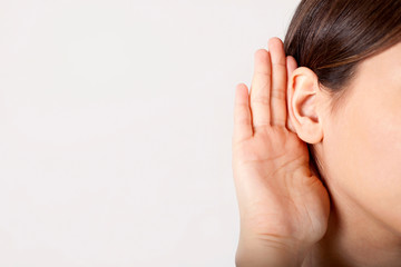 young woman holding her ear to listen