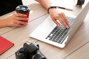 Young female photographer working on laptop at table