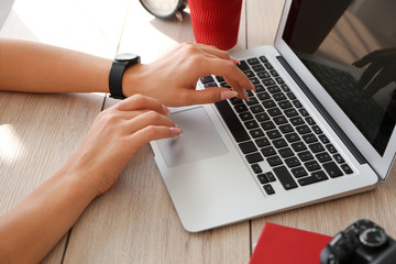 Young female photographer working on laptop at table