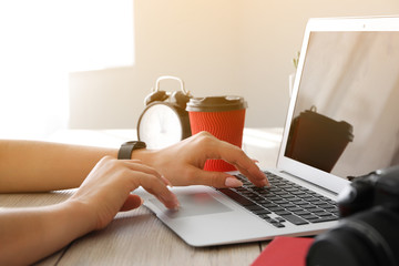 Young female photographer working on laptop at table