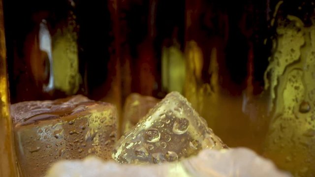 cold beer bottles with ice cubes closeup. dolly shot