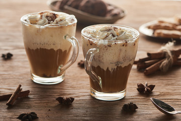Christmas cacao with whipped cream on wooden table with spices