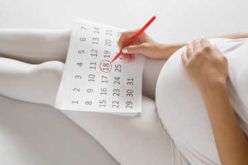 Fototapeta Young pregnant woman marking childbirth day in calendar. Baby expecting concept. Planning of future. obraz