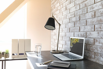 Comfortable workplace near light brick wall