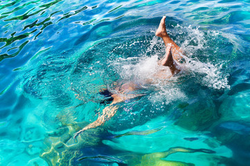 Young girl with diving mask and snorkel dives in clear blue sea water, adult woman in white bikini swims in turquoise clean transparent ocean water, tropical coral reef snorkeling on summer holidays