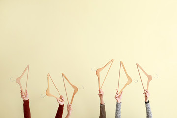 Female hands with clothes hangers on light background