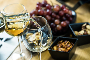 Pouring white wine into the glass against wooden table